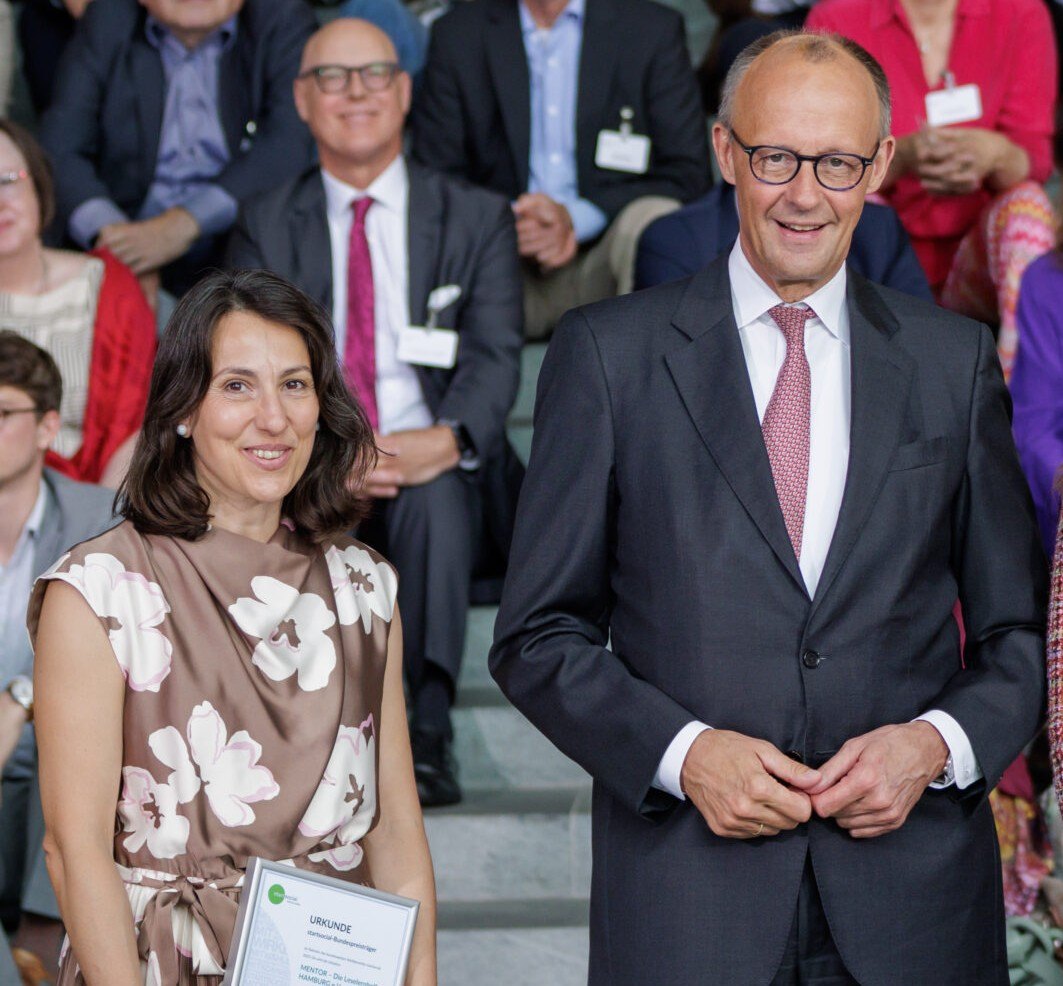 Linda Nikolova mit der Urkunde und Bundeskanzler Friedrich Merz bei der Verleihung des startsocial-Bundespreises 2026